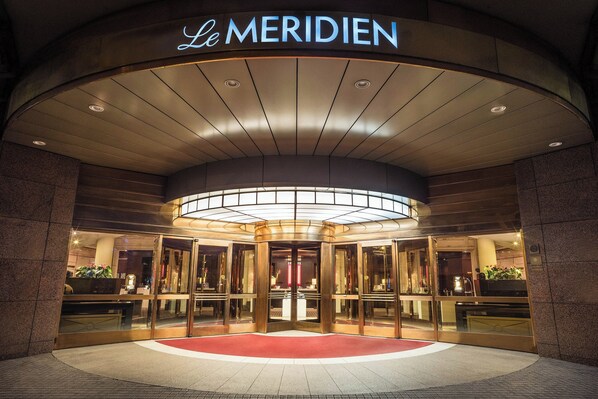 The entrance of Le Meridien hotel with a revolving door and a red carpet leading to the lobby.