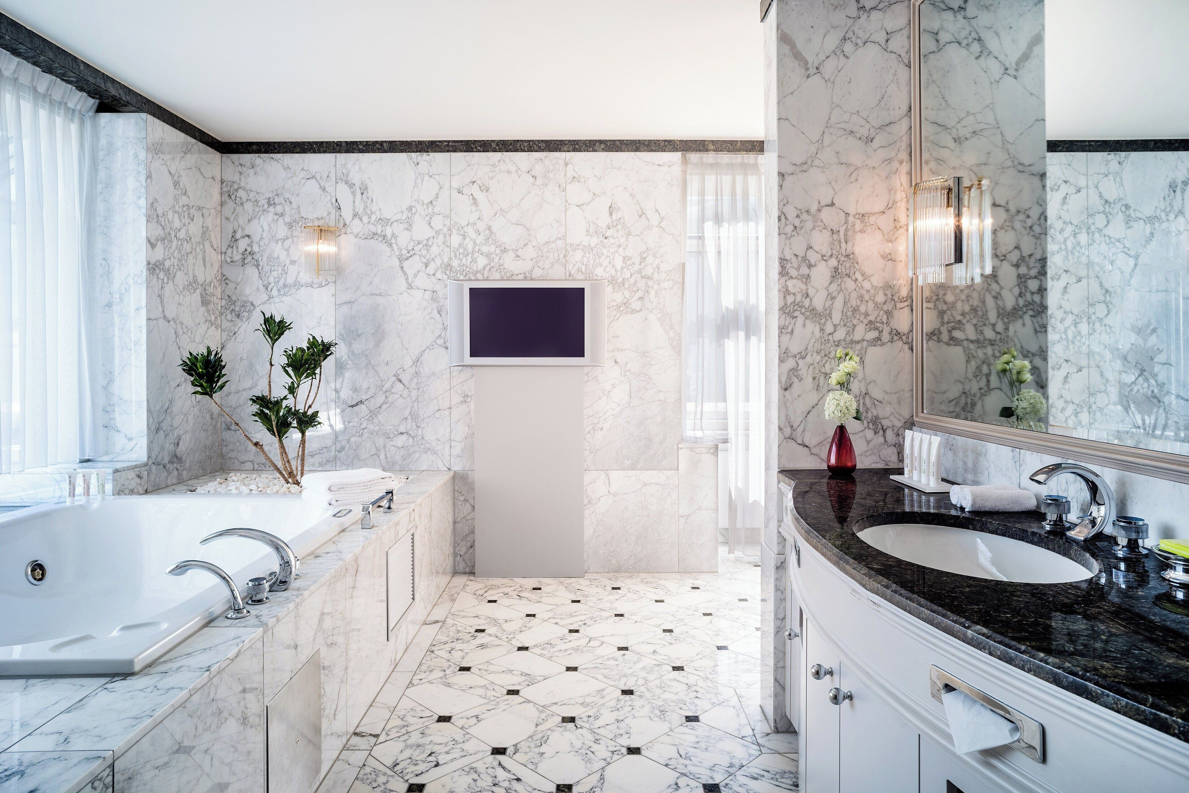 A modern bathroom with a large bathtub, a sink, and a mirror.