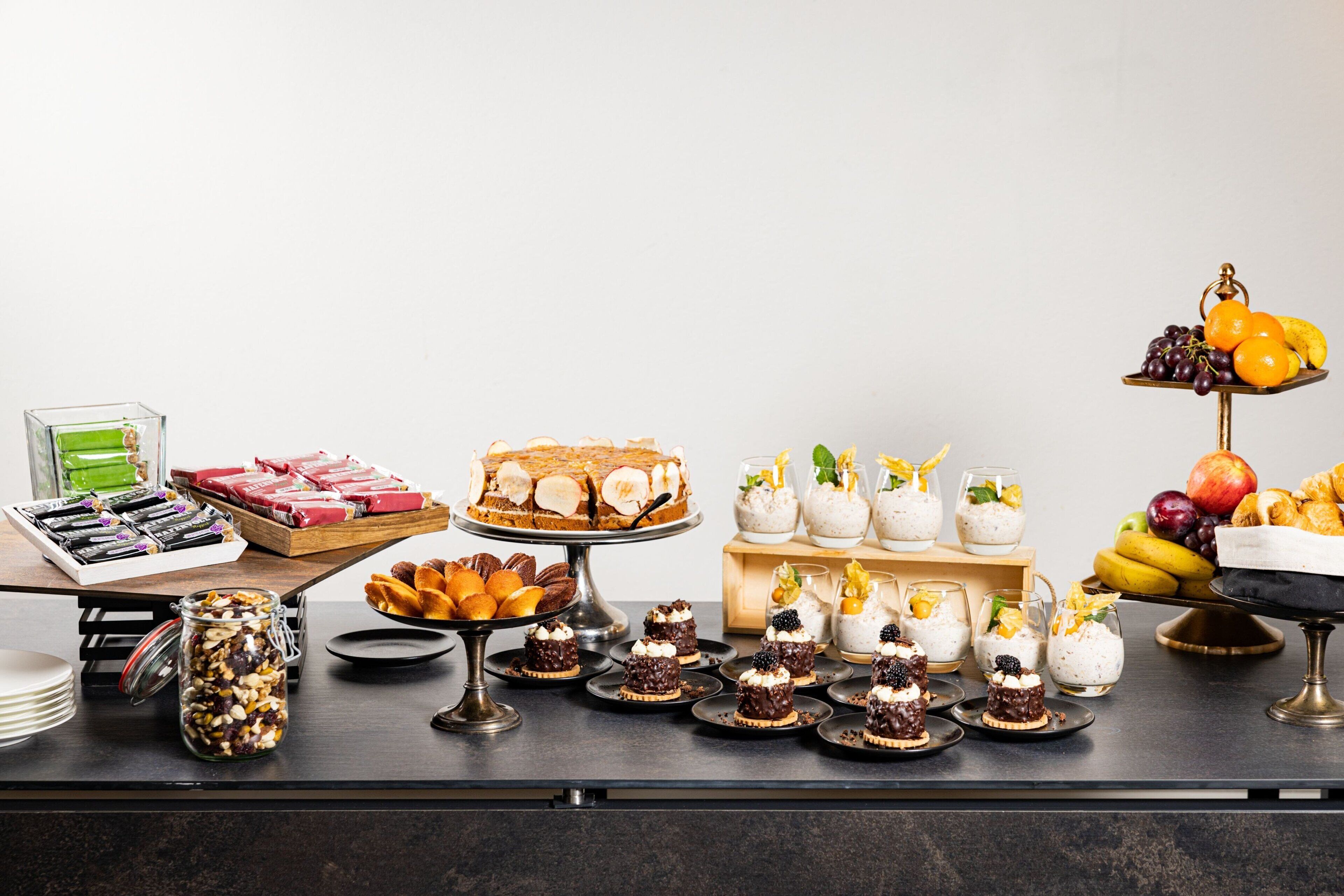 Una mesa de buffet con diversos alimentos, incluyendo pasteles, bollos y fruta.