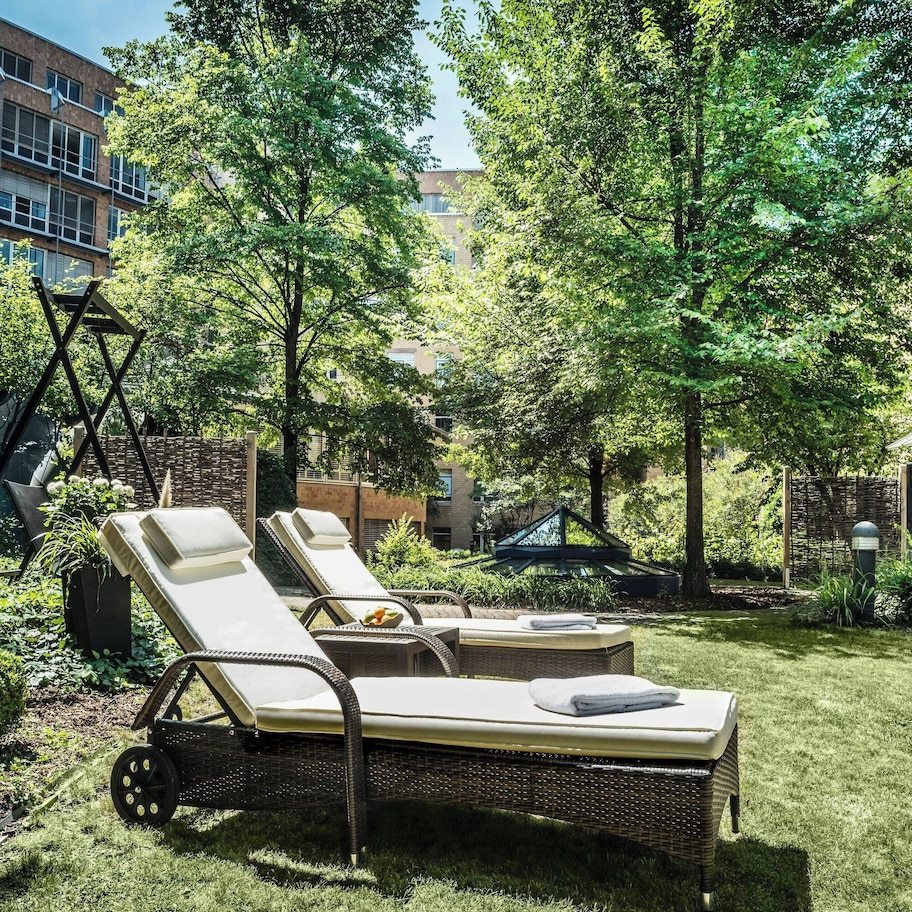 A courtyard with lounge chairs, a swing set, and a brick building in the background.