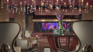 Um interior moderno com uma mesa redonda, cadeiras e um vaso decorativo com flores.