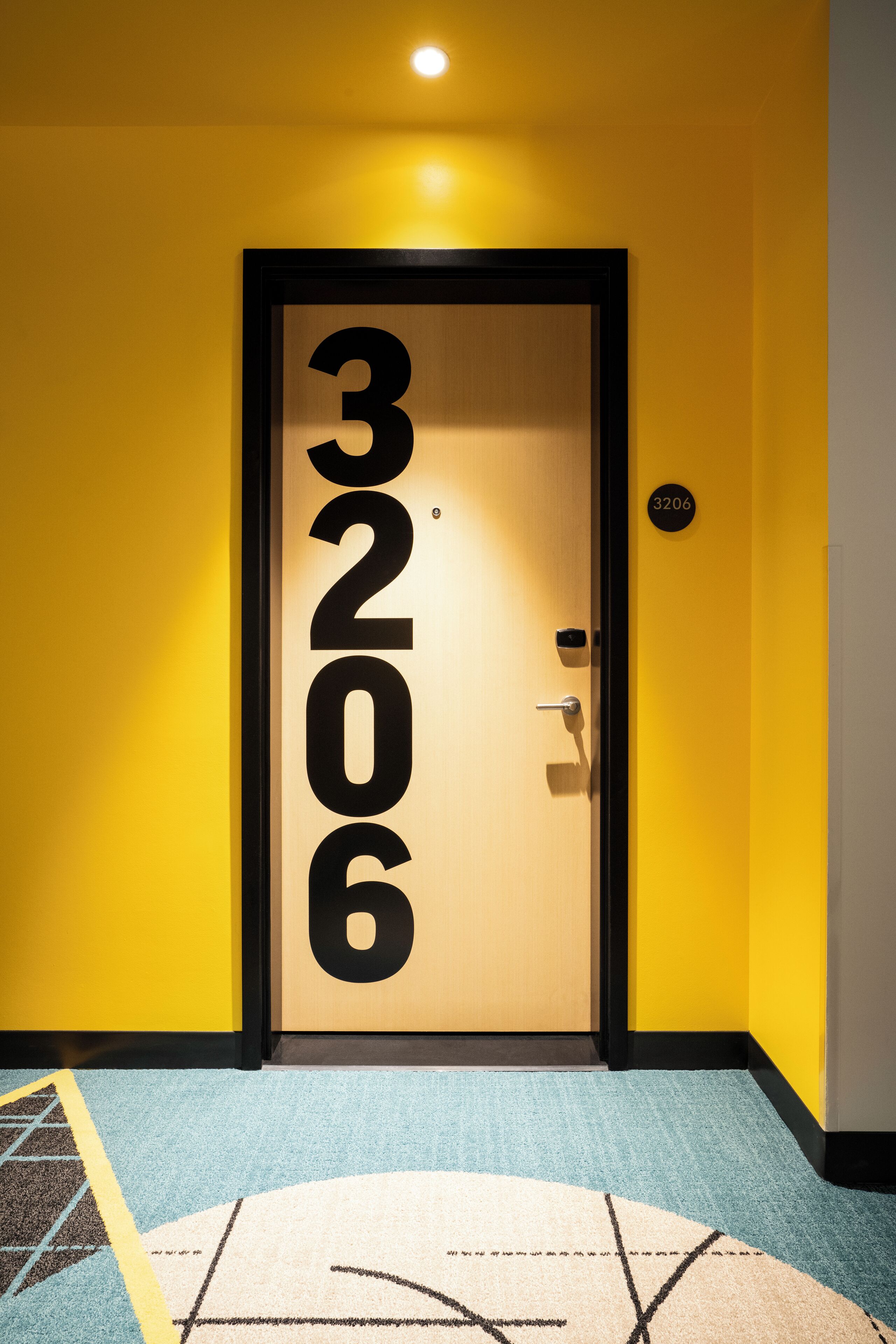 A door with the number 3206, a black door frame, and a small sign above the door.