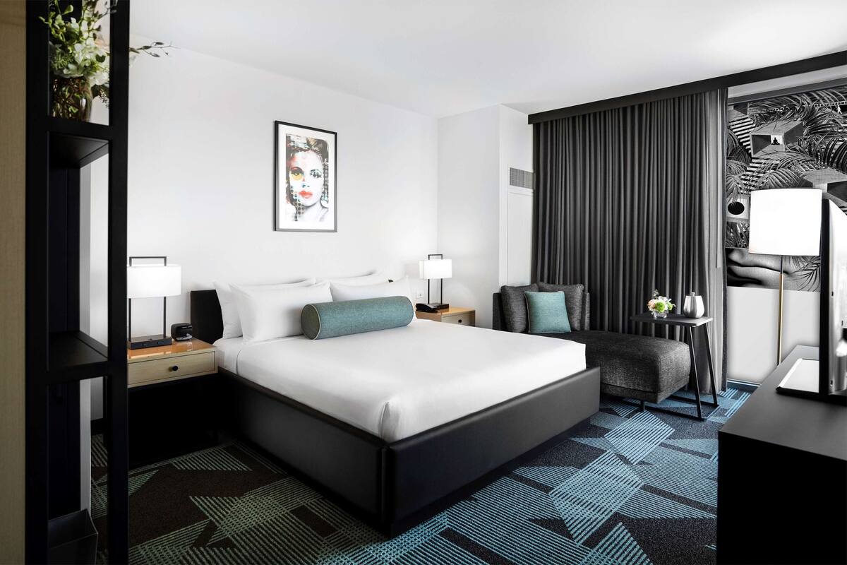 Quarto de hotel moderno com uma cama grande, uma escrivaninha e uma cadeira.