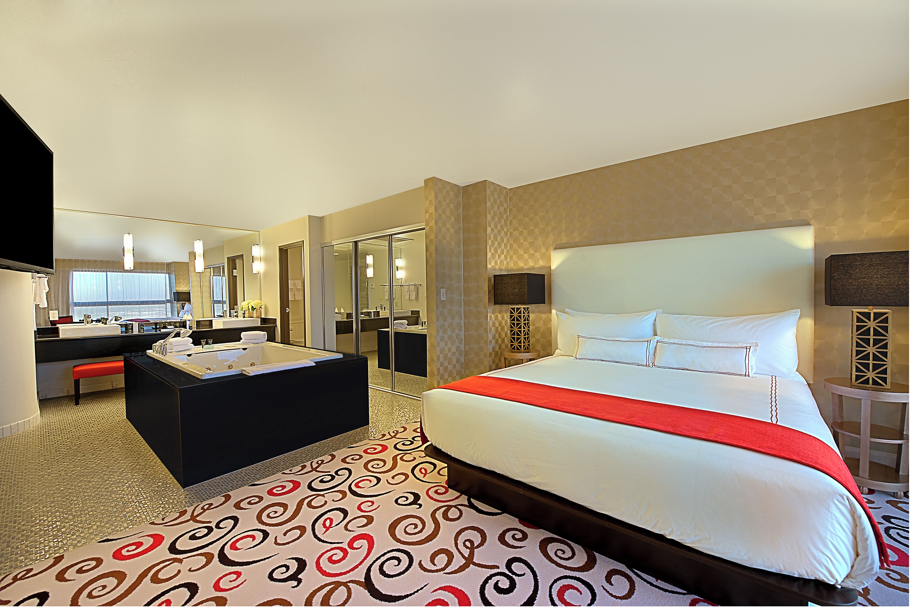 Une chambre d’hôtel avec un grand lit, une salle de bain séparée avec une baignoire, un bureau et une chaise.