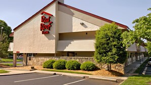 A Red Roof Inn with a stone facade, a red roof, and a parking lot. - Red Roof Inn Greensboro Coliseum (Greensboro)