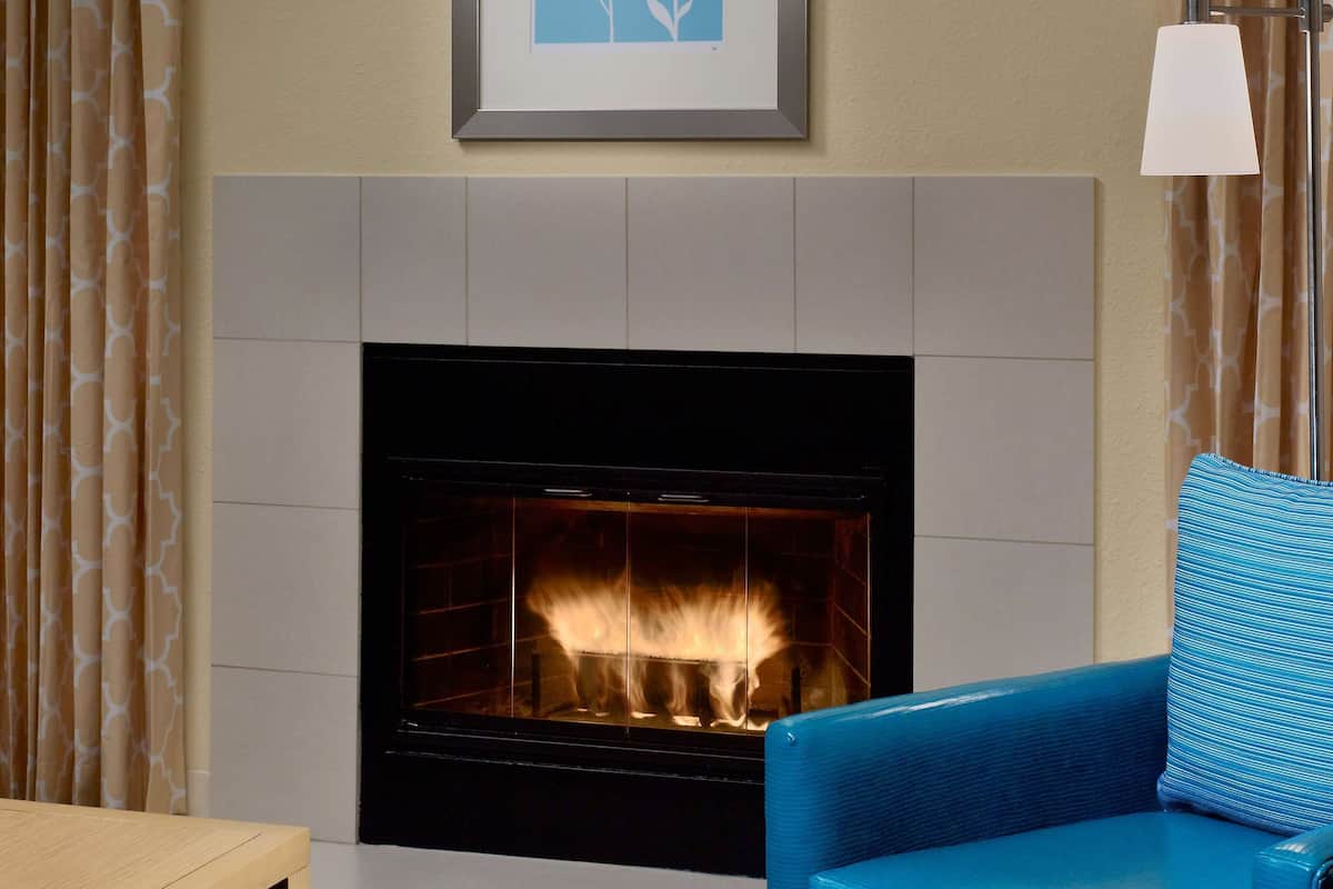 A living room with a fireplace, a framed picture above it, and a blue armchair.