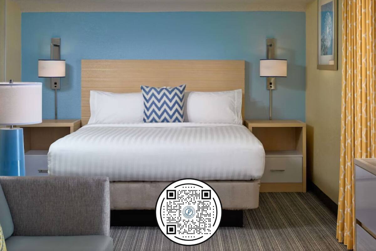 A hotel room with a bed, two bedside tables with lamps, a sofa, and a TV.