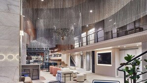 A spacious lobby with a high ceiling, seating areas, a bar, and a staircase. - Hotel Silken Ramblas (Barcelona)