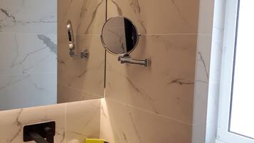 Un bany modern amb un respatller de marbre, un mirall rodó, un lavabo amb dispensador de sabó i un suport per a tovalloles.