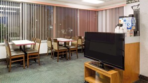 Una habitación de hotel con televisión, muebles de madera y un amplio ventanal con persianas.