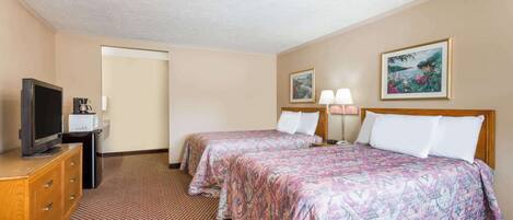 A hotel room with two beds, a television, a coffee maker, and artwork on the walls.