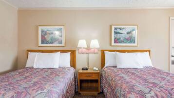 A hotel room with two beds, a nightstand with lamps, and framed pictures on the wall.