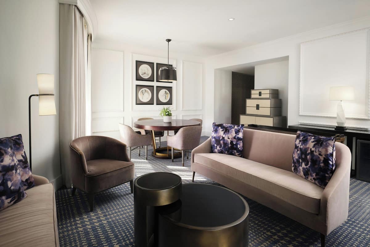 A modern living room with a sofa, armchairs, a coffee table, and a dining area with a table and chairs.