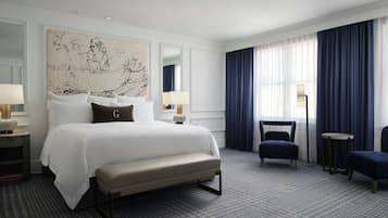 A hotel room with a large bed, a bench, two chairs, a desk, and a large abstract painting on the wall.