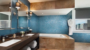 A modern bathroom with dual sinks, a large bathtub, and a blue mosaic tile wall.