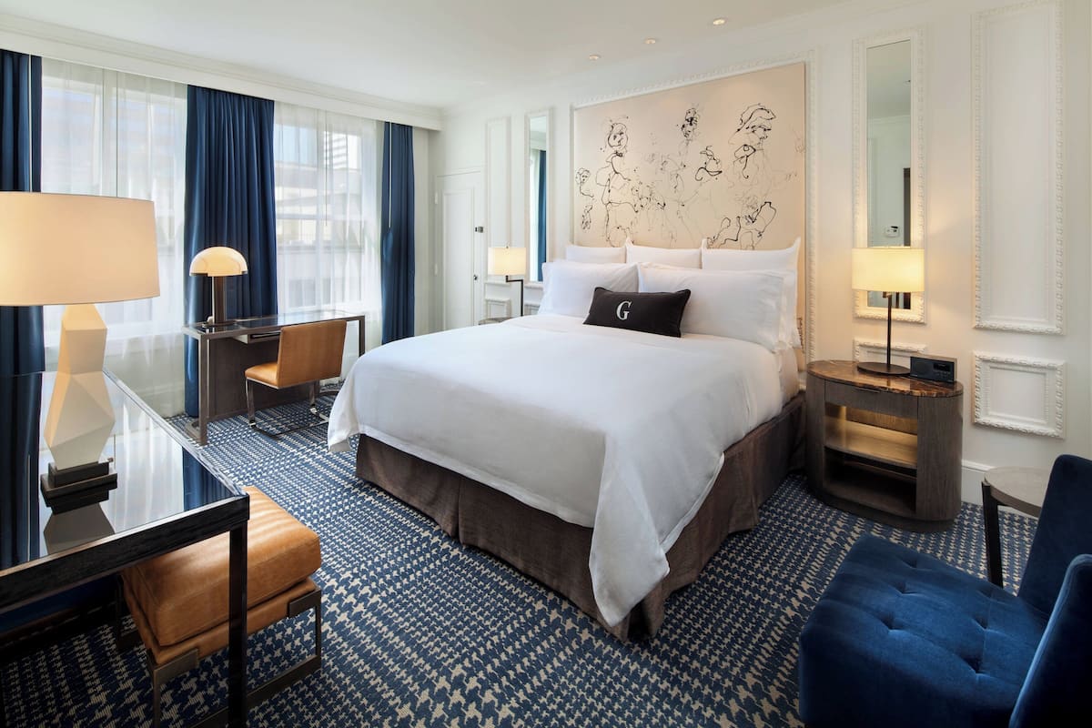A hotel room with a large bed, two bedside tables, a desk, and a chair.