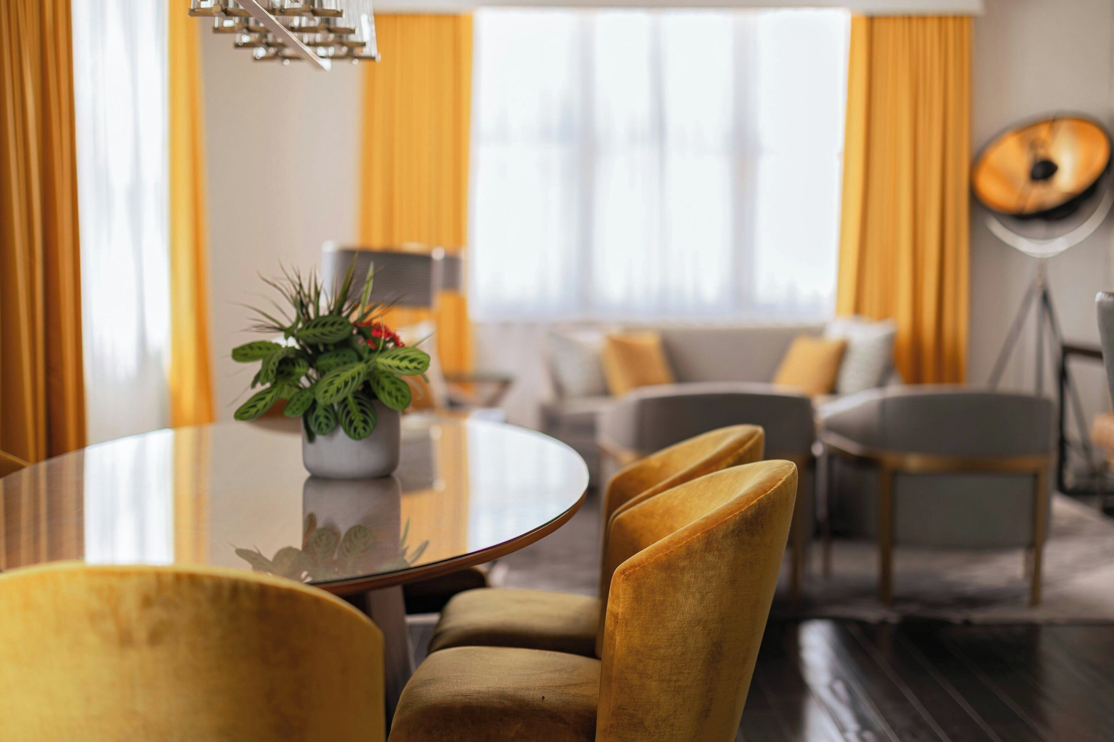 Un espace repas moderne avec une table ronde, des chaises jaunes et une plante en pot.
