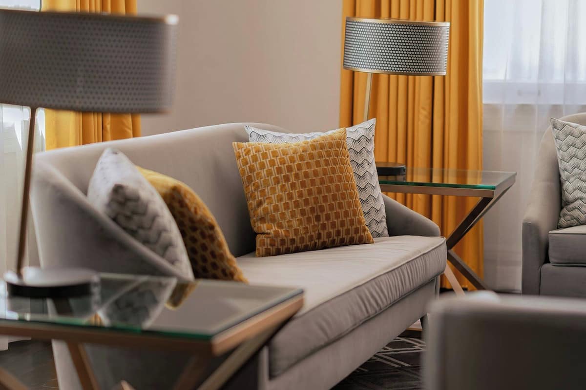 A modern living room with a sofa, a glass coffee table, and a lamp.
