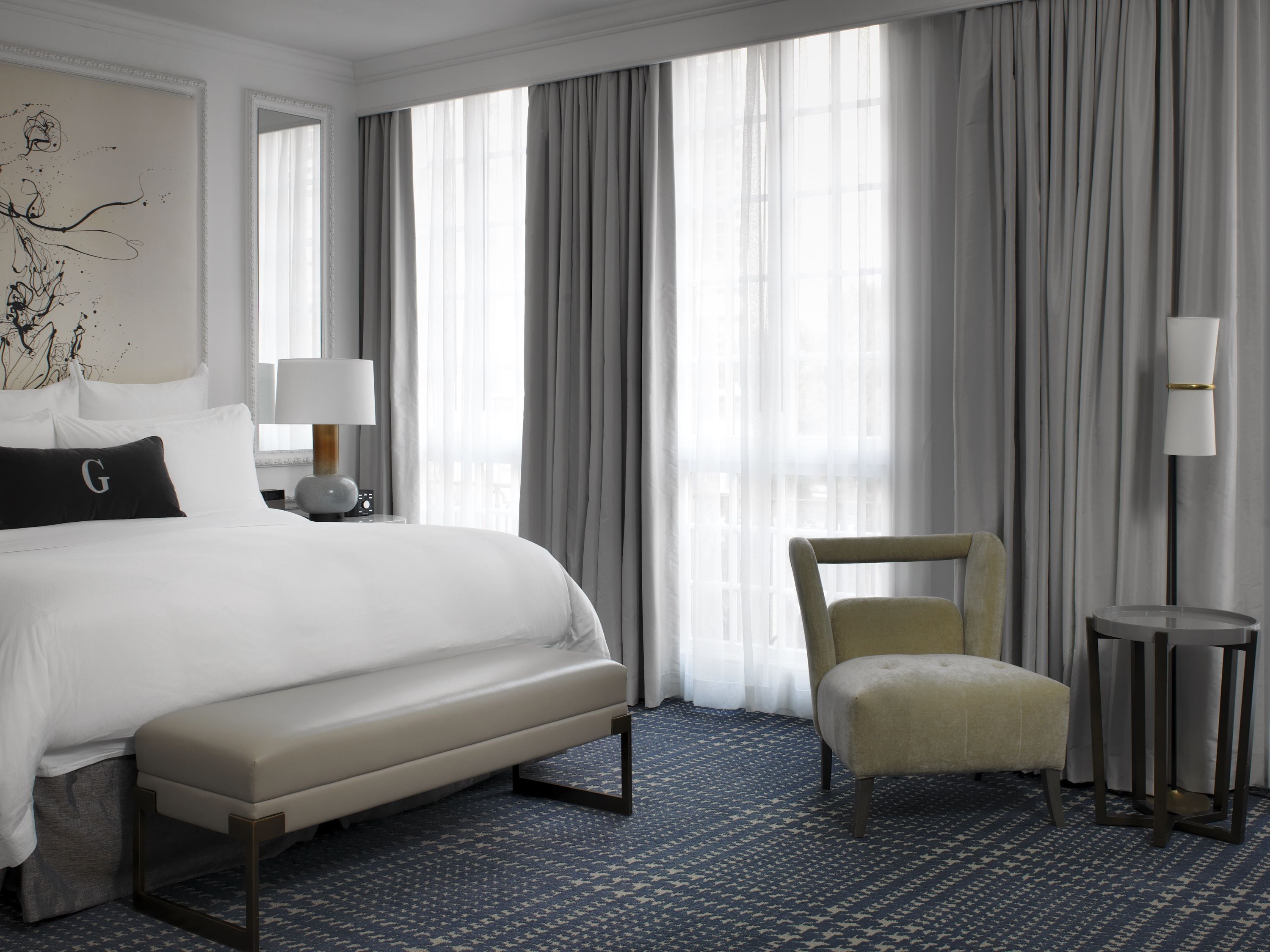 Habitación de hotel con una cama grande, una silla, un escritorio y una lámpara.