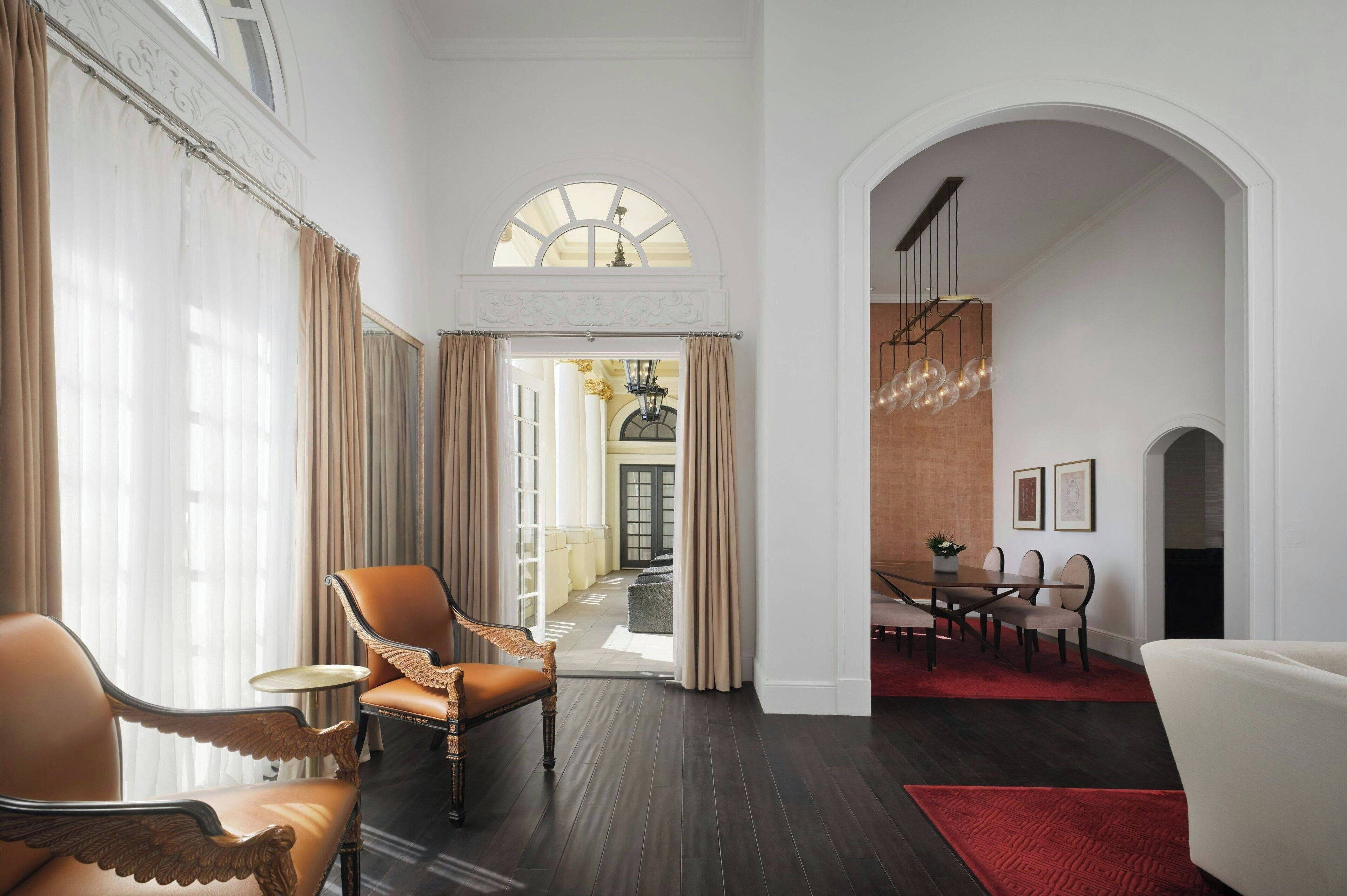A spacious hotel lobby with a grand staircase, a dining area, and elegant seating arrangements.