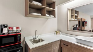 A modern bathroom with a built-in microwave, a sink, and wooden shelves above the counter. - Red Roof Inn PLUS+ Chicago - Hoffman Estates (Hoffman Estates)