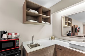 A modern bathroom with a built-in microwave, a sink, and wooden shelves above the counter. - Red Roof Inn PLUS+ Chicago - Hoffman Estates (Hoffman Estates)