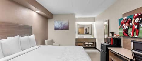 Une chambre d’hôtel avec un grand lit, un bureau, un four à micro-ondes et une télévision.