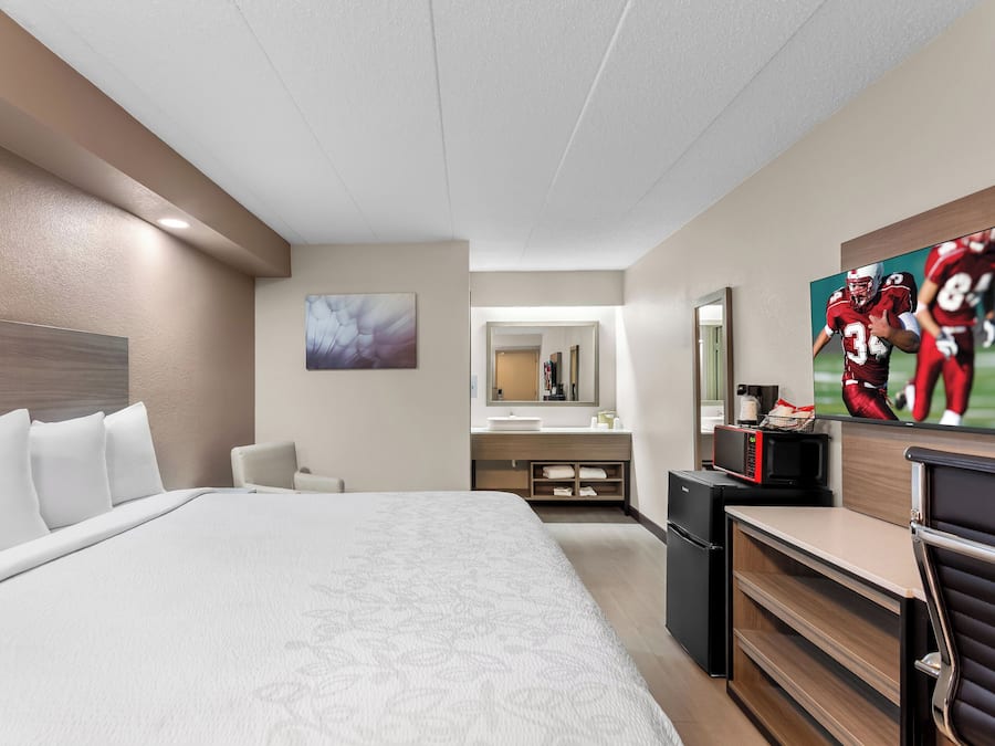 Quarto de hotel com uma cama grande, uma mesa, micro-ondas e televisão.