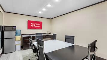 A conference room with a long table, four chairs, a microwave, a refrigerator, and a water dispenser. A sign indicates free Wi-Fi is available in all rooms.