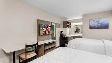 A hotel room with two beds, a desk, a TV, a microwave, and a coffee maker.