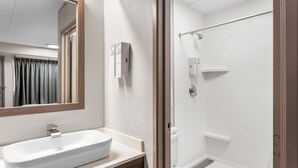 A bathroom with a white sink, mirror, and shower. - Red Roof Inn PLUS+ Chicago - Hoffman Estates (Hoffman Estates)