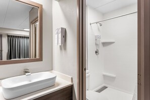 A bathroom with a white sink, mirror, and shower. - Red Roof Inn PLUS+ Chicago - Hoffman Estates (Hoffman Estates)
