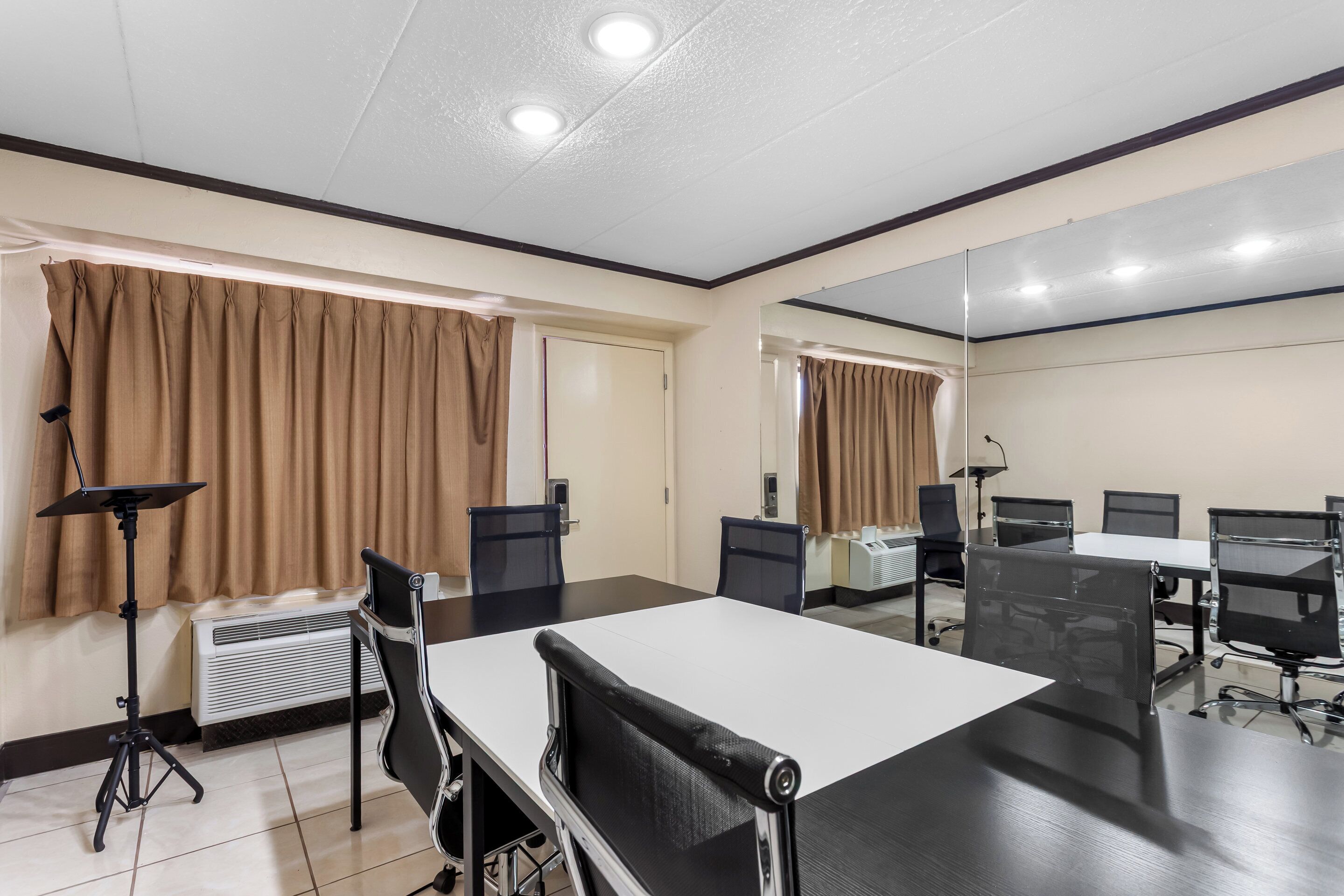 A conference room with a large table, chairs, a standing lamp, and an air conditioning unit.