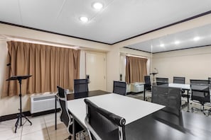 A conference room with a large table, chairs, a standing lamp, and an air conditioning unit. - Red Roof Inn PLUS+ Chicago - Hoffman Estates (Hoffman Estates)