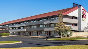 A Red Roof Inn with a two-story structure, a parking lot, and a clear sky. - Red Roof Inn PLUS+ Chicago - Hoffman Estates (Hoffman Estates)