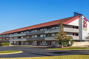 A Red Roof Inn with a two-story structure, a parking lot, and a clear sky. - Red Roof Inn PLUS+ Chicago - Hoffman Estates (Hoffman Estates)