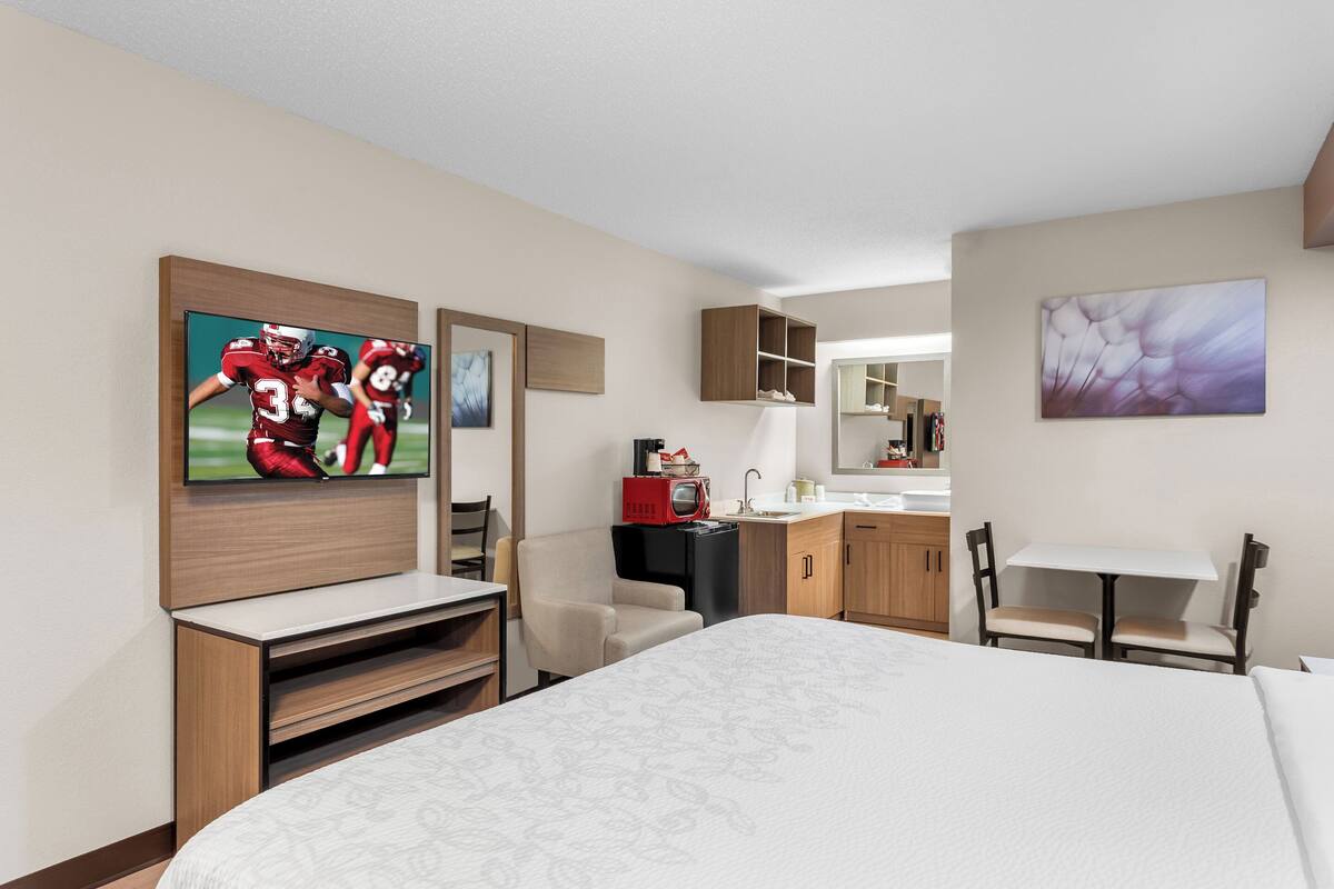 Ein Hotelzimmer mit Bett, Fernseher, Küchenzeile und Sitzecke.