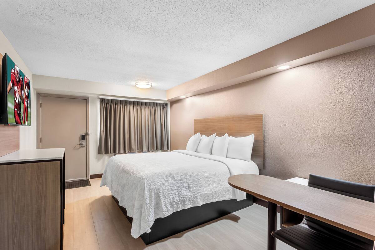 Ein modernes Hotelzimmer mit einem großen Bett, einem Schreibtisch und einem Esstisch.