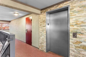 An elevator with a stone wall and a red door. - Red Roof Inn PLUS+ Chicago - Hoffman Estates (Hoffman Estates)
