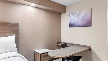 A hotel room with a bed, a desk, and a chair.