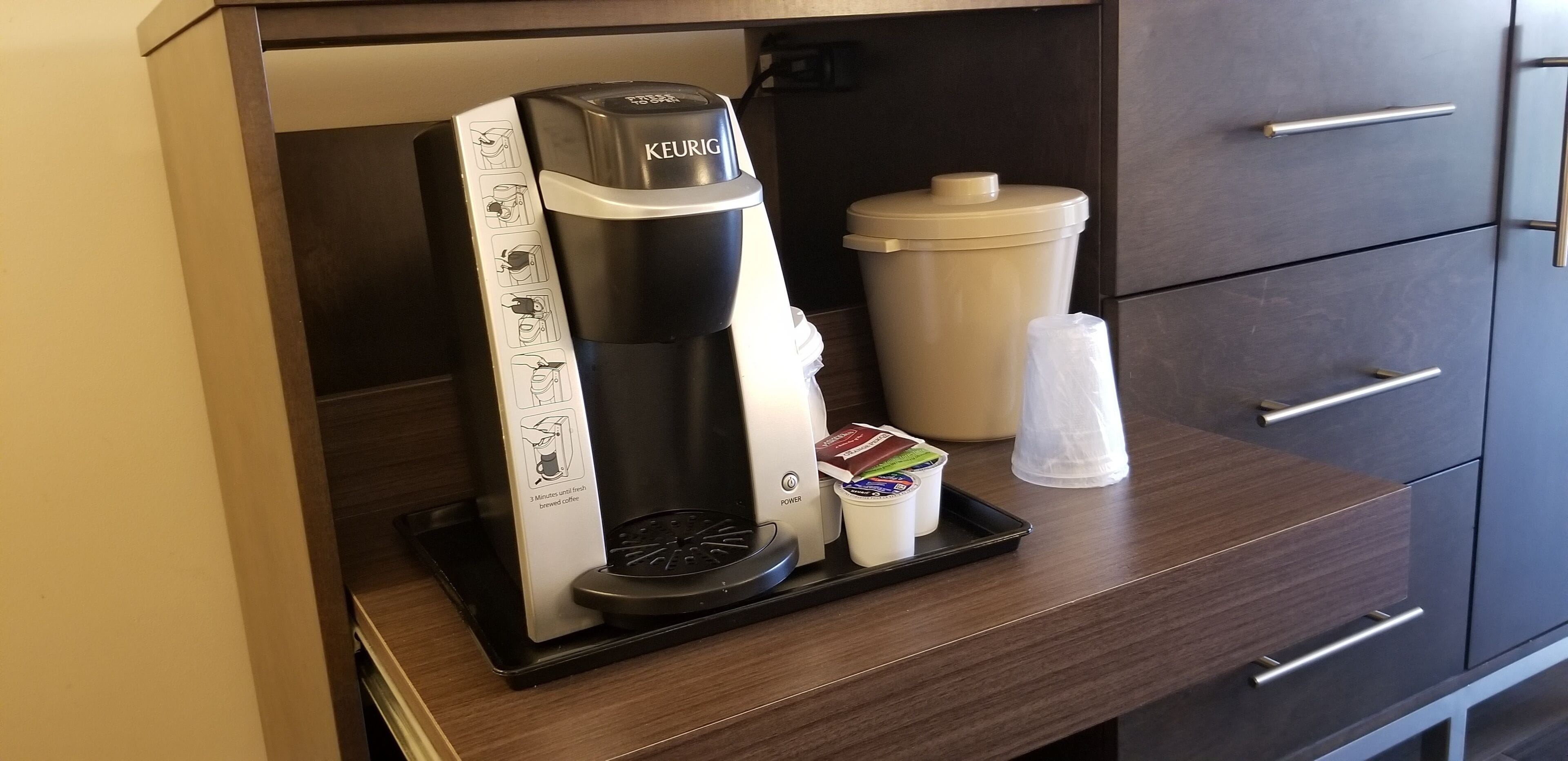 A Keurig coffee machine with a drip tray, a coffee pod holder, and a disposable cup on a countertop.