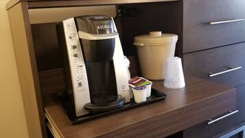 A Keurig coffee machine with a drip tray, a coffee pod holder, and a disposable cup on a countertop.