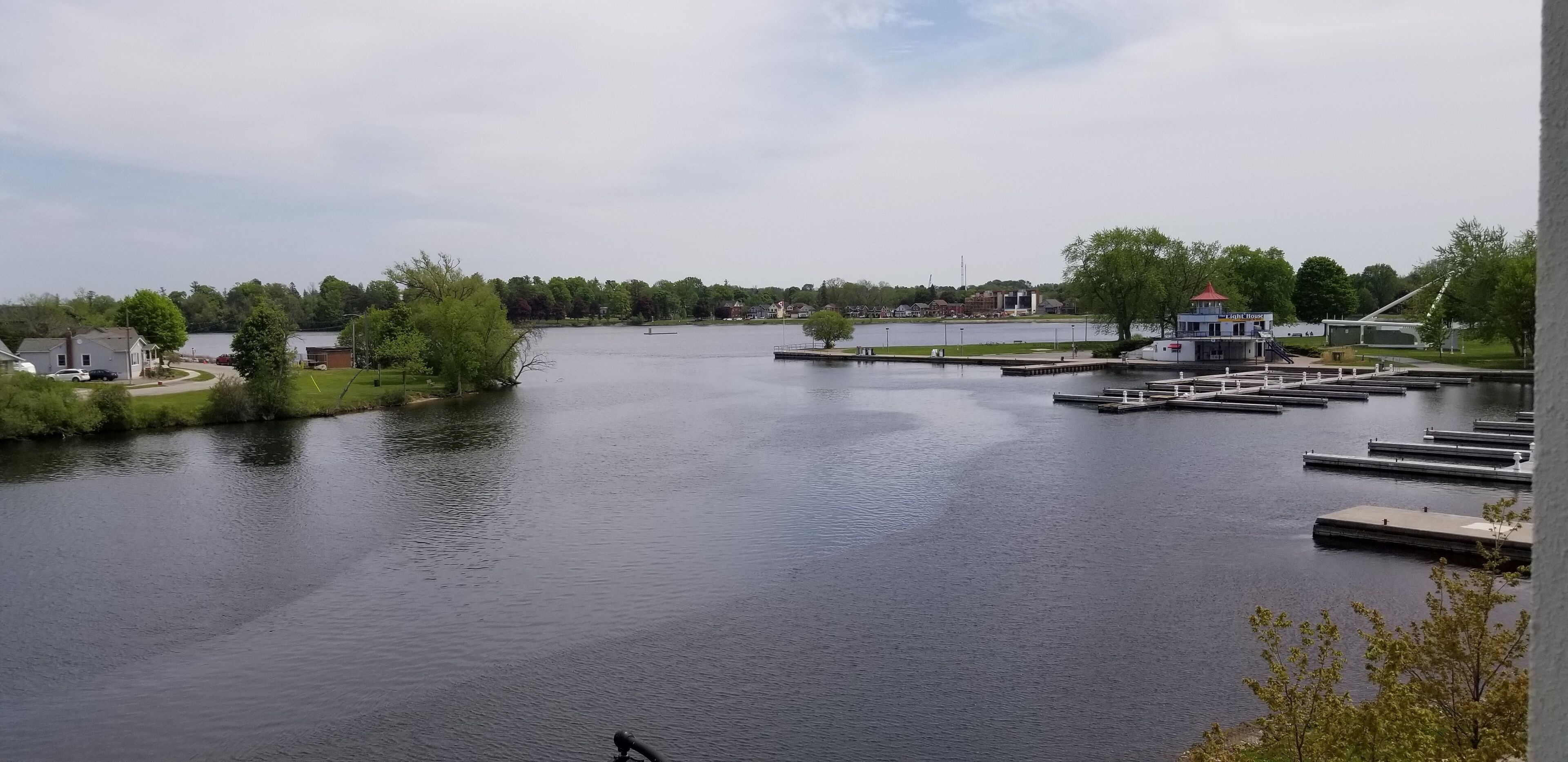 A calm lake with docks, a small building labeled 'Light House', and a distant shoreline with trees and houses.