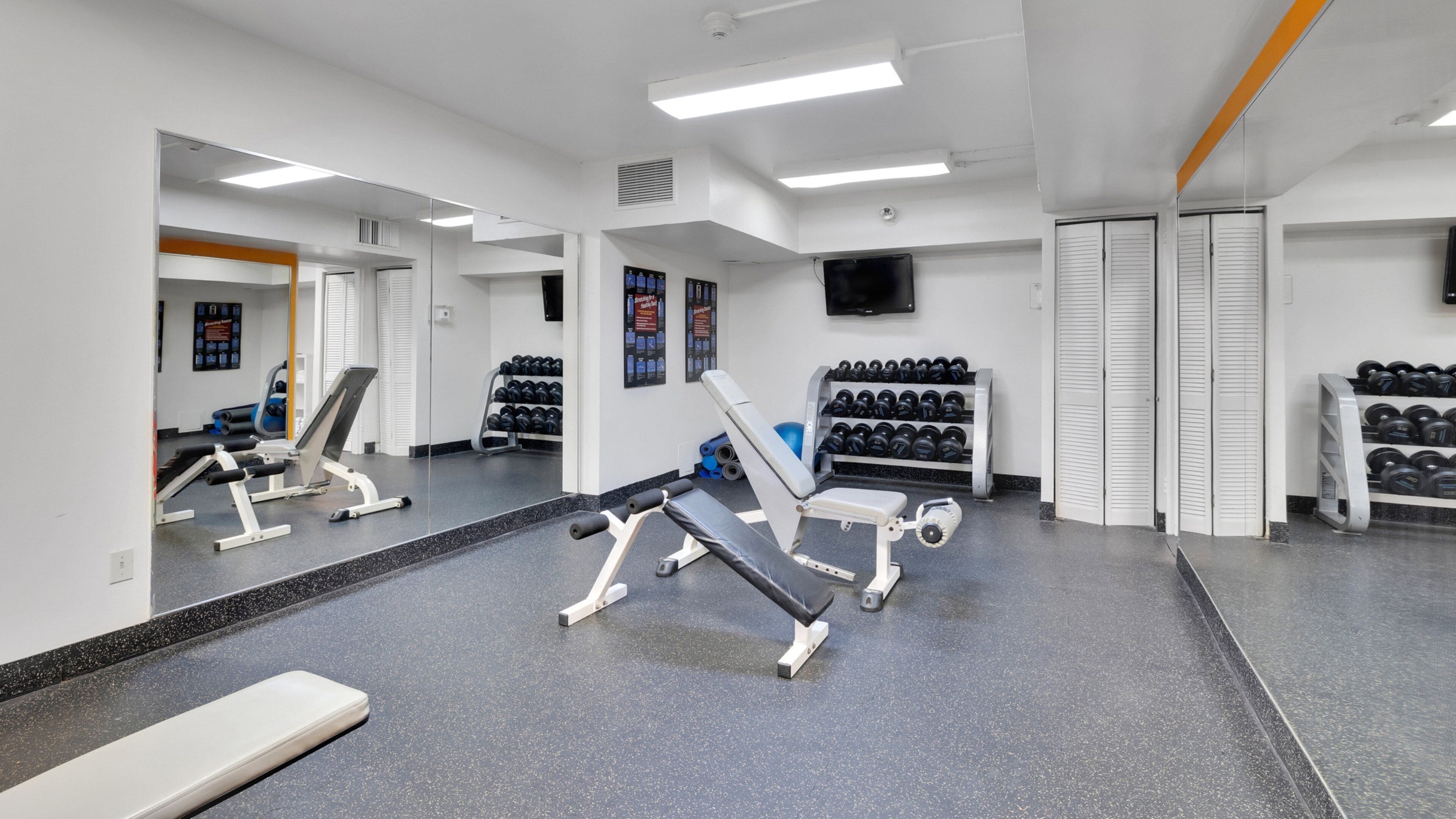 A gym with exercise equipment, mirrors, and weight racks.
