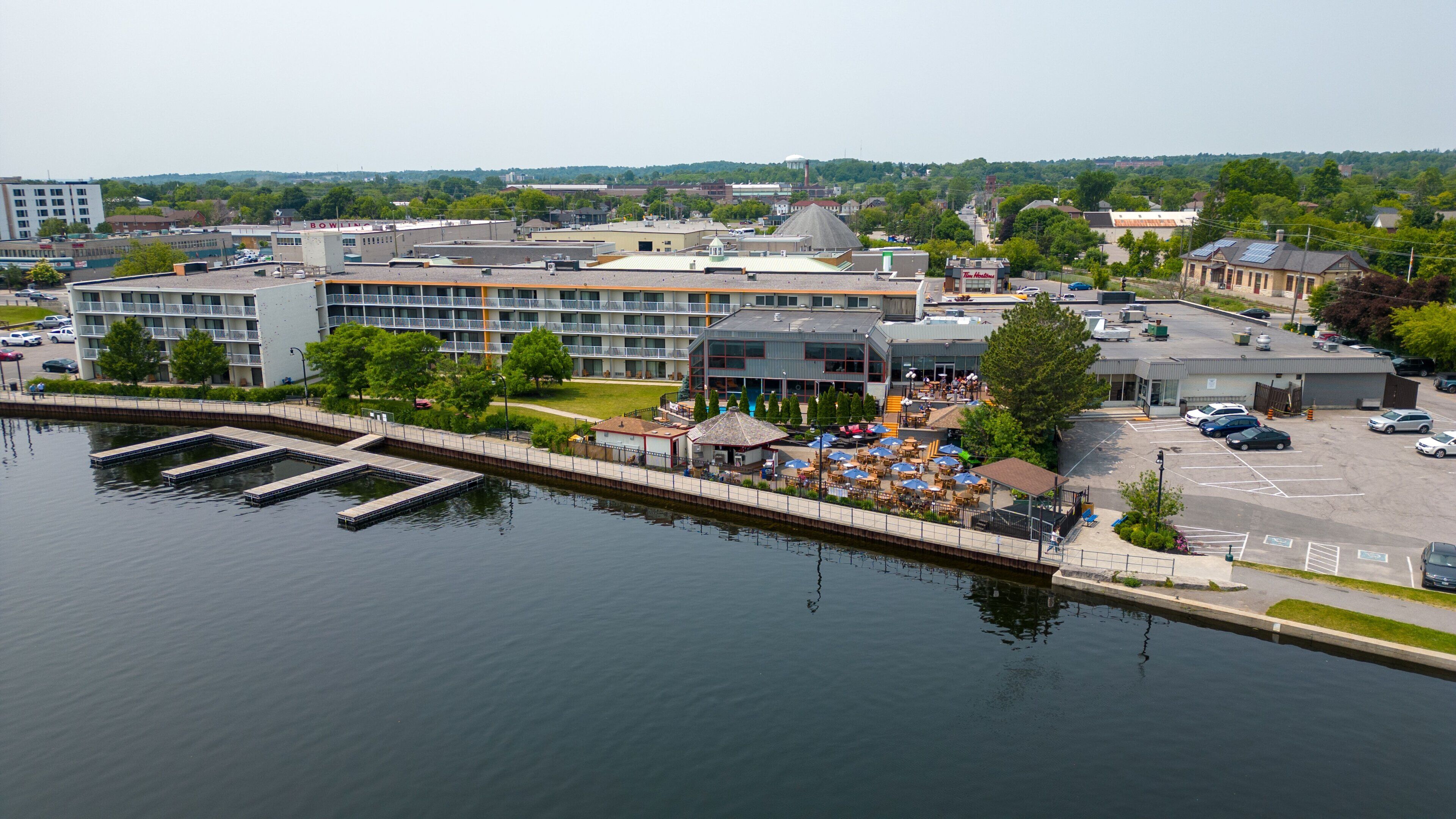 A waterfront hotel with a pool, outdoor seating, and a view of the city.