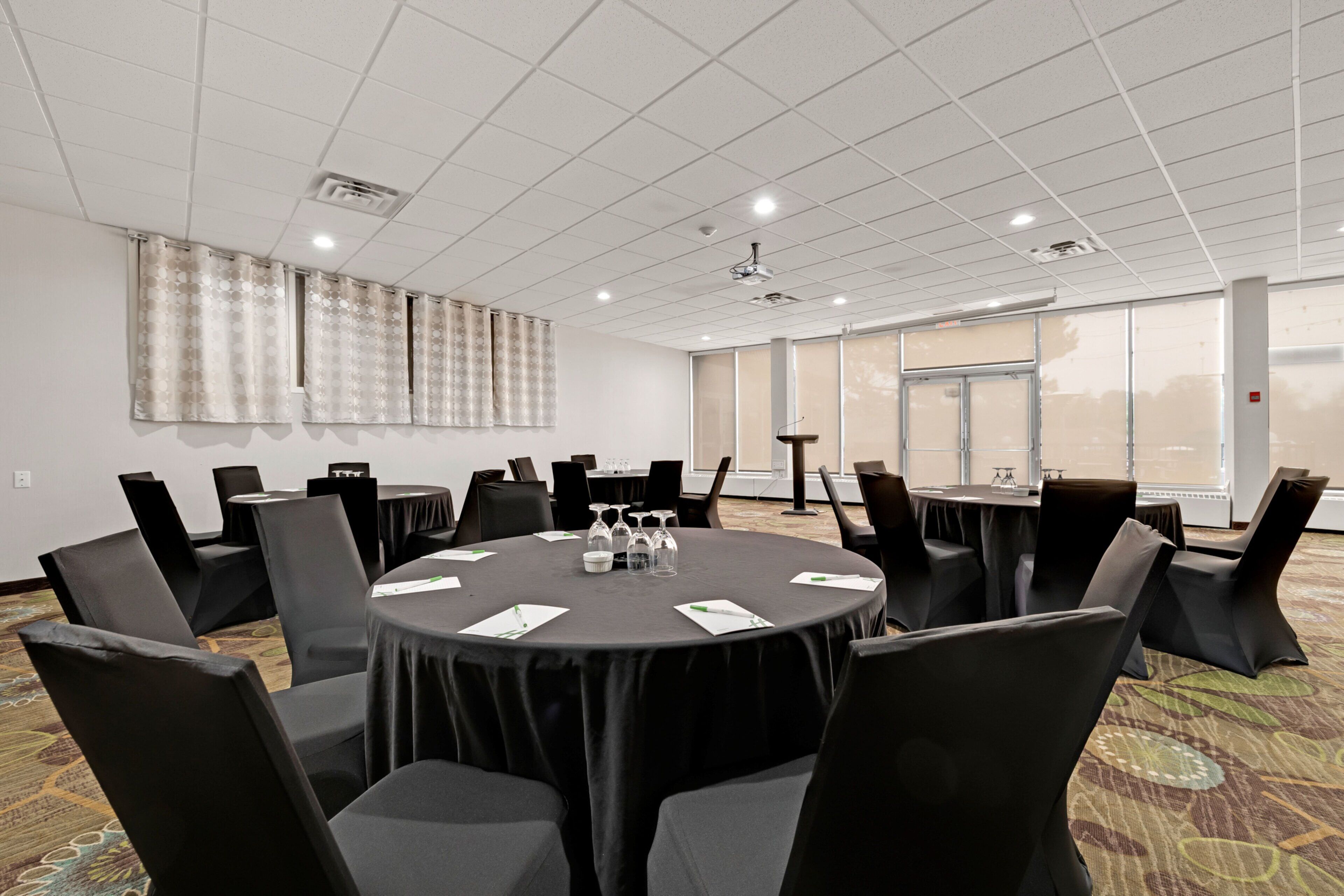 A conference room with a round table, black chairs, and a carpeted floor.
