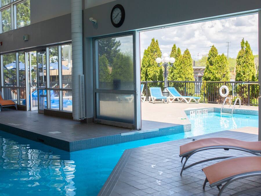 En inomhuspool med väggar av genomskinligt glas, solstolar och utsikt över omgivningen.