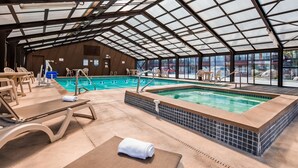 An indoor swimming pool with a glass ceiling, lounge chairs, and a hot tub. - Best Western Paradise Inn (Dillon)