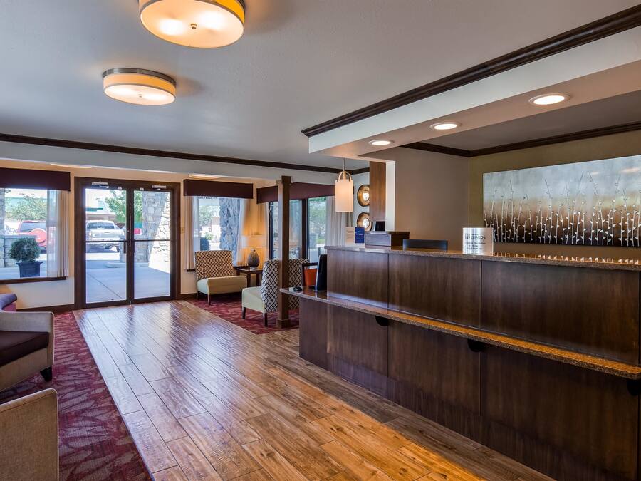 Een hotel lobby met een receptiebalie, een zithoek en grote ramen.