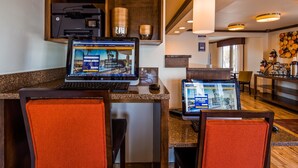 A hotel reception area with two HP computers, a coffee machine, and a wall-mounted clock. - Best Western Paradise Inn (Dillon)